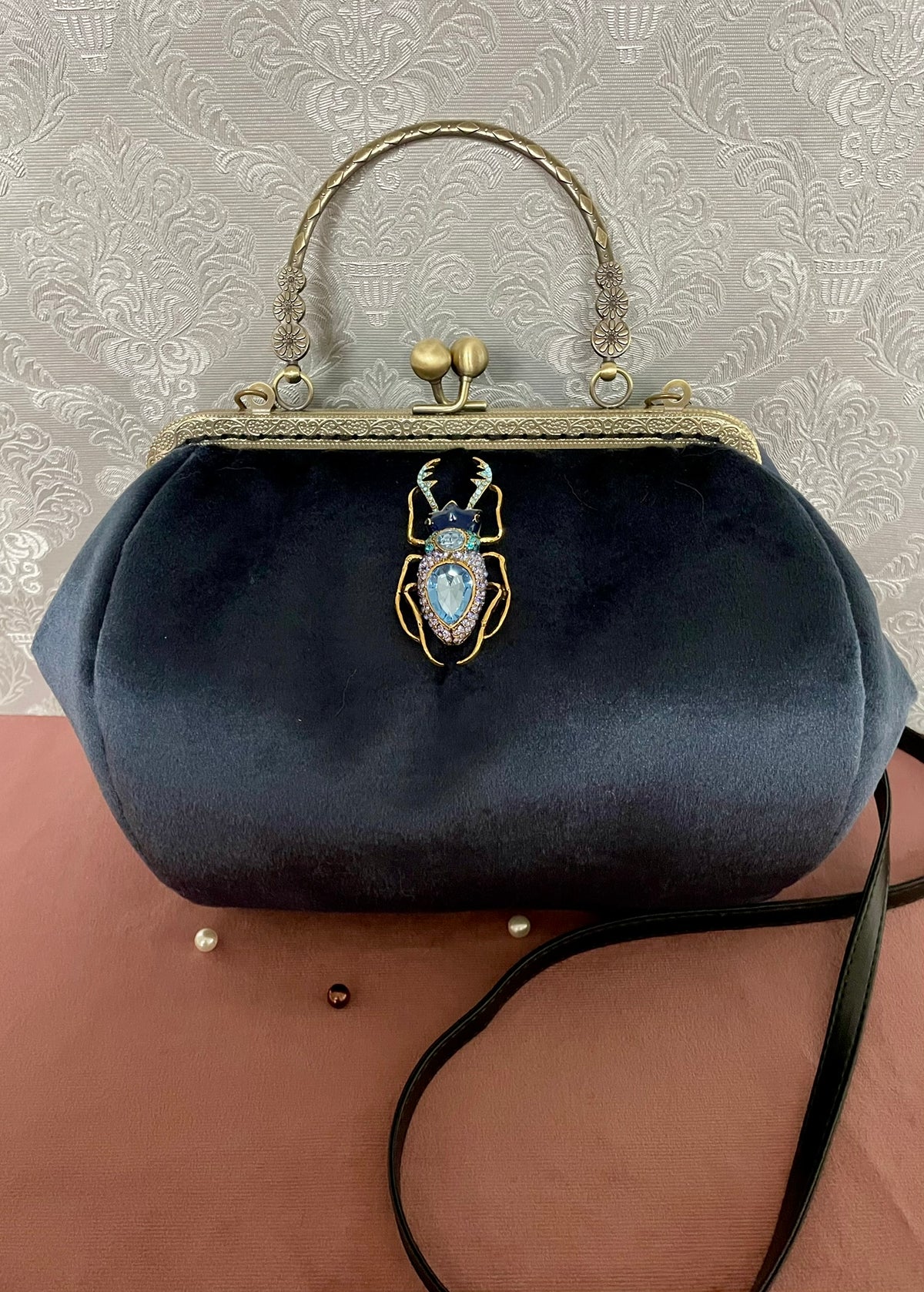 Sac rétro en velours bleu nuit orné d'un bijou scarabée doré et strass bleus avec poignée et lanière noire Le Comptoir de Suzanne