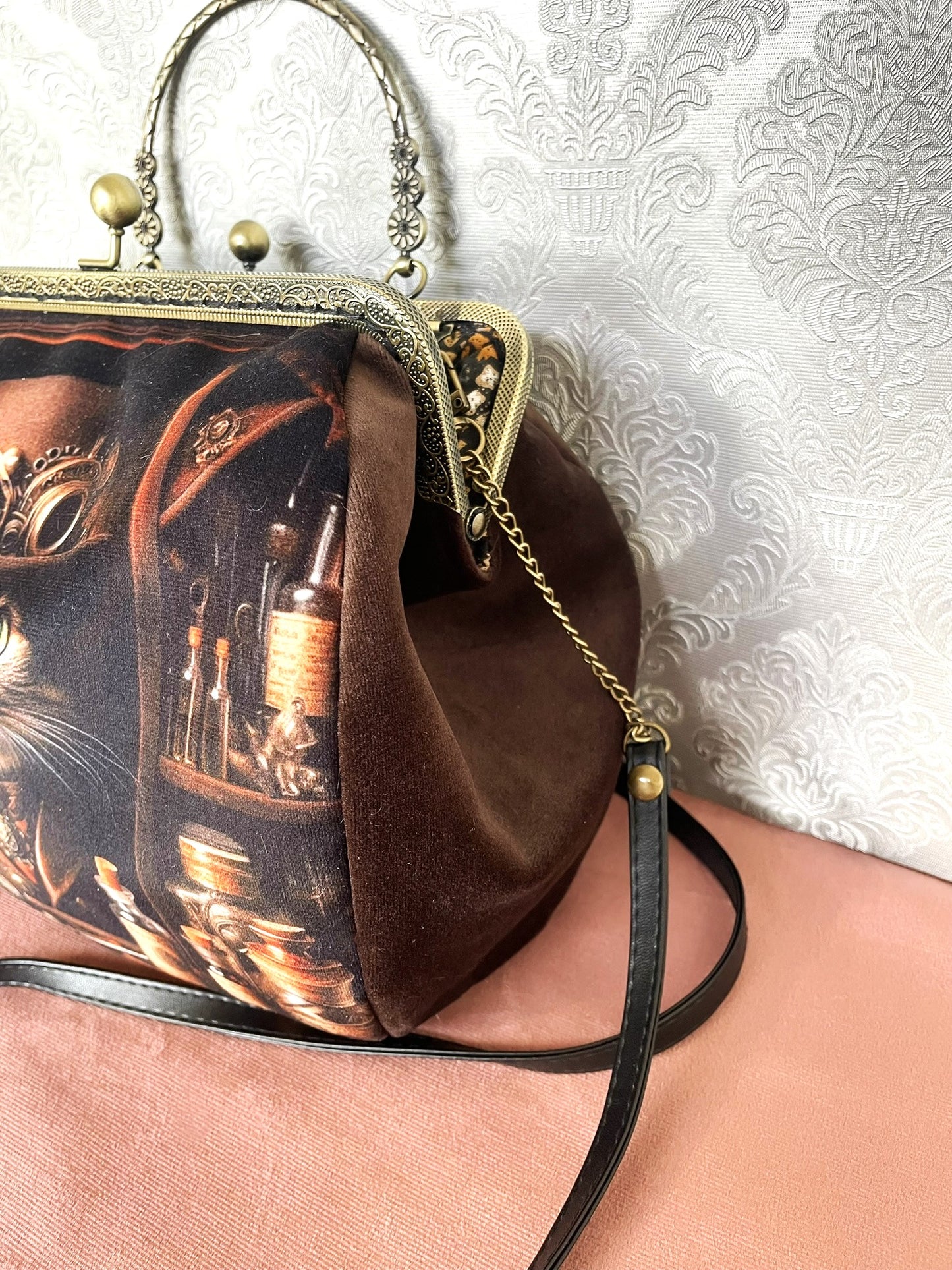 Soufflet en velours marron et détails du fermoir métallique avec poignée effet bronze ciselée sur un sac de créateur.