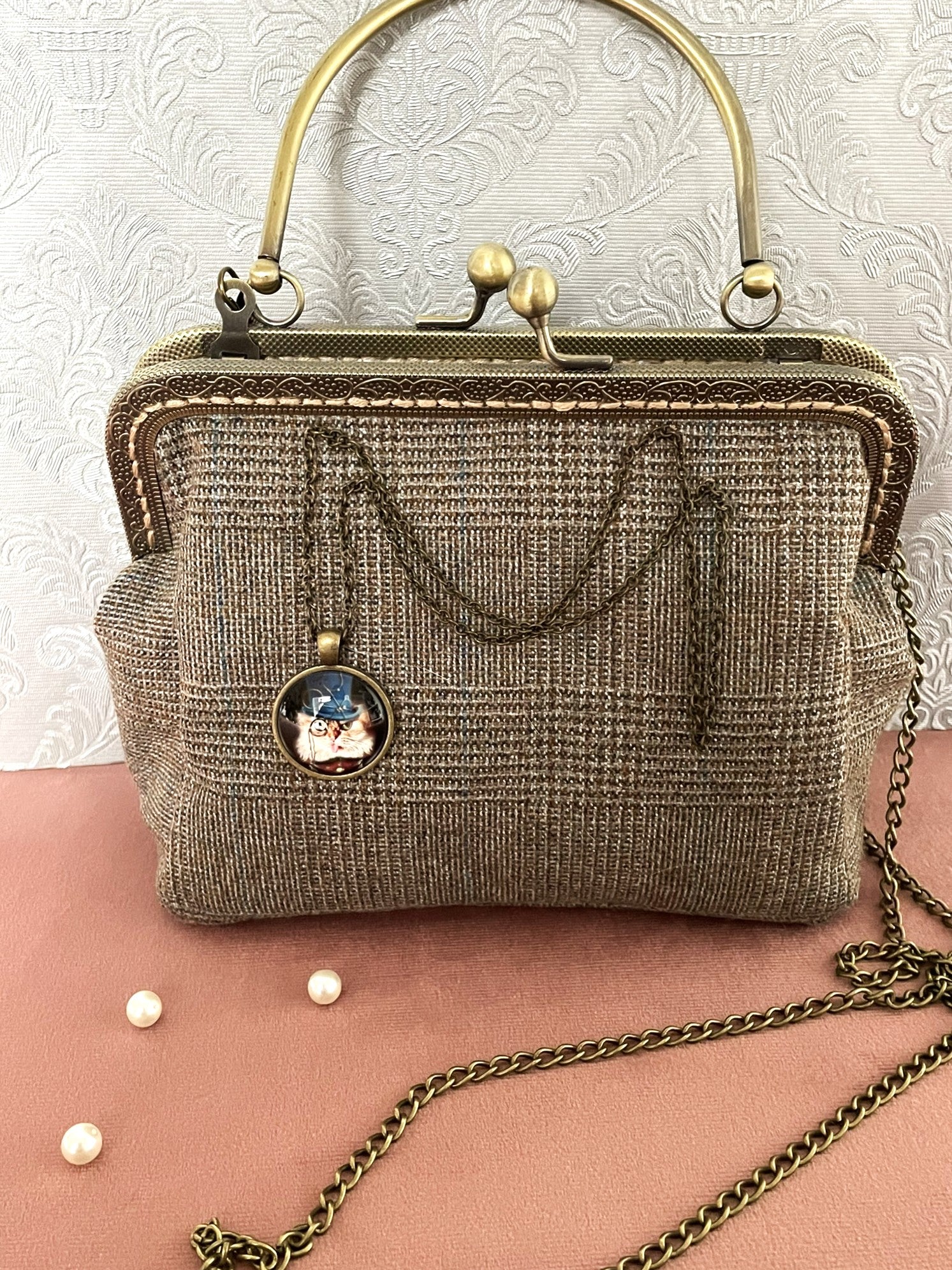 Vue de face du sac bandoulière en tweed de laine avec anse rigide, fermoir clac vintage et sa longue chaîne en métal .