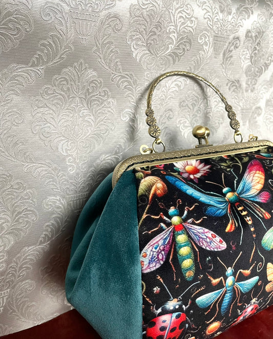 Vue de côté d'un sac rétro à fermoir vintage en velours vert canard avec imprimé insectes multicolores