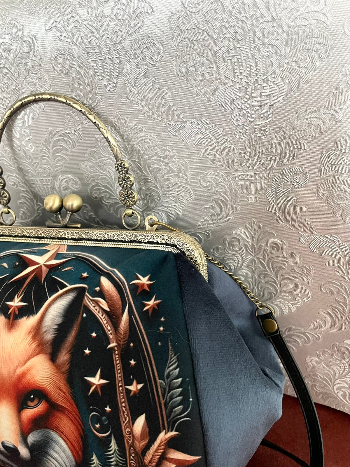 Gros plan sur le profil du sac rétro en velours bleu gris avec attaches bandoulière et poignée