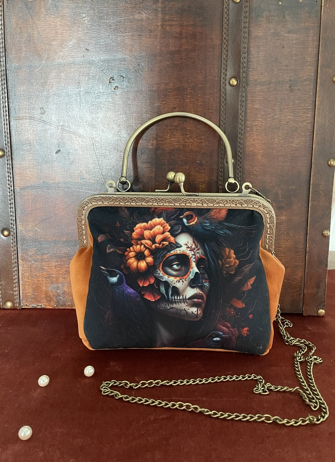 Sac à main illustré Santa Muerte avec velours ocre et poignée bronze.