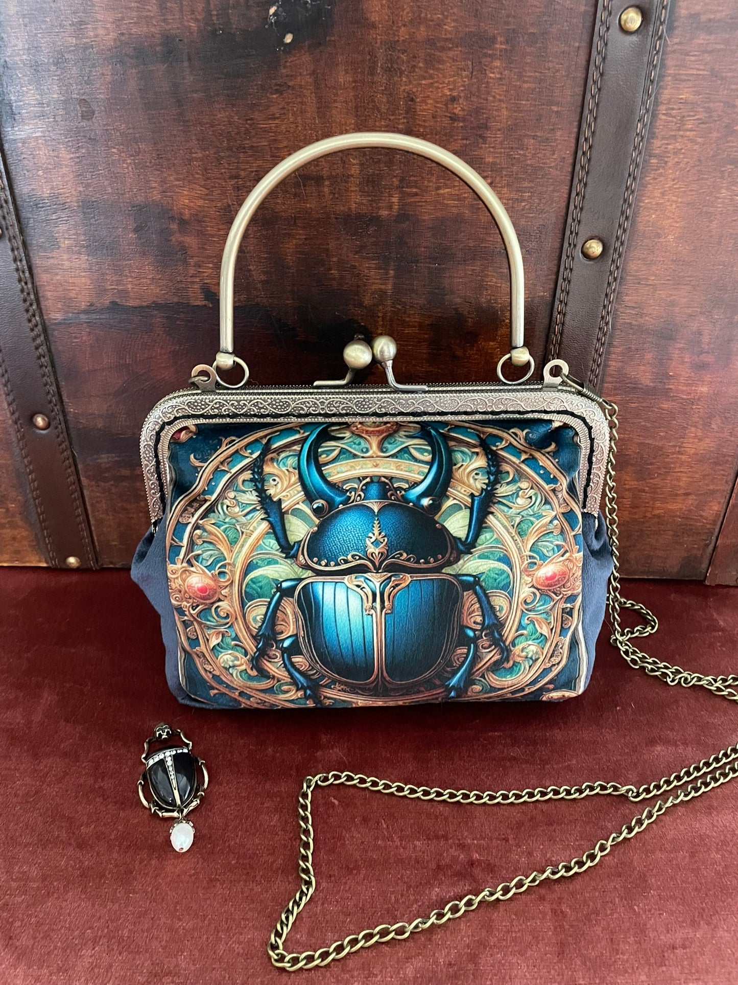 Sac scarabée posé devant une malle ancienne en bois vintage